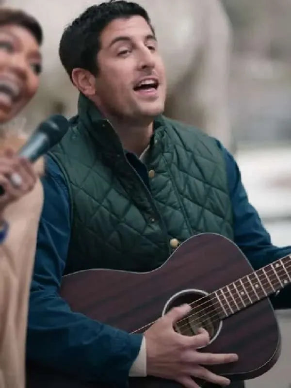 Man in green quilted vest playing guitar and singing outdoors