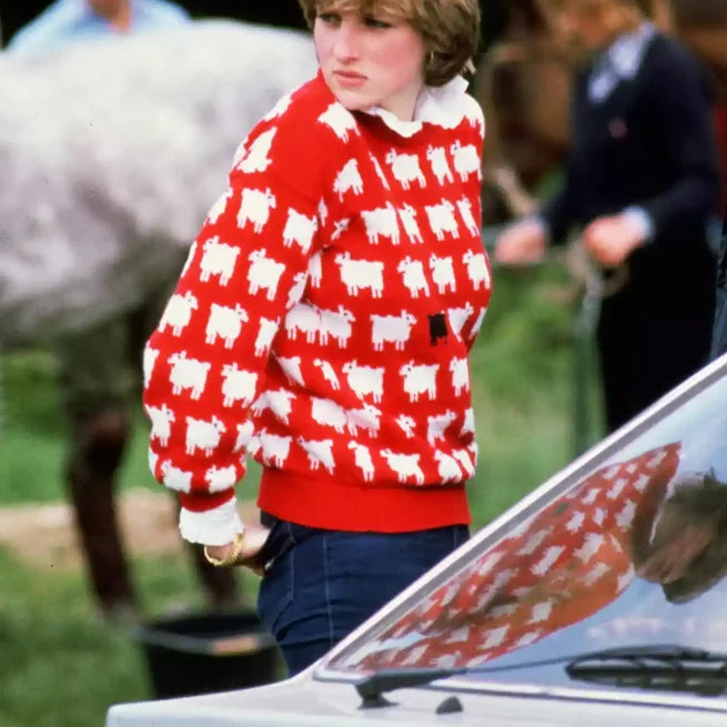 Woman in red sweater with white and black sheep pattern standing outdoors by a car