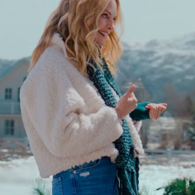 Woman wearing a white faux fur jacket and scarf outdoors in a snowy winter setting