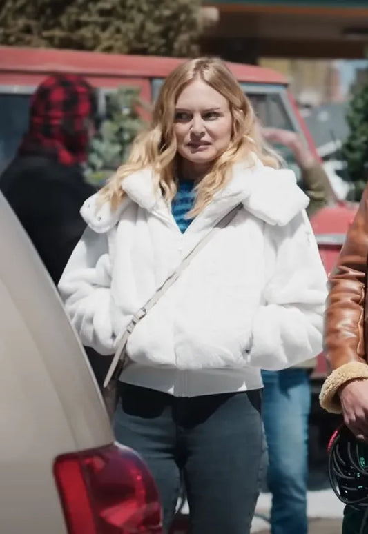 Woman in white winter jacket and blue jeans standing outdoors by cars and trees