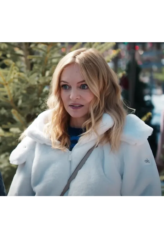 Woman in a white jacket standing outdoors near Christmas trees