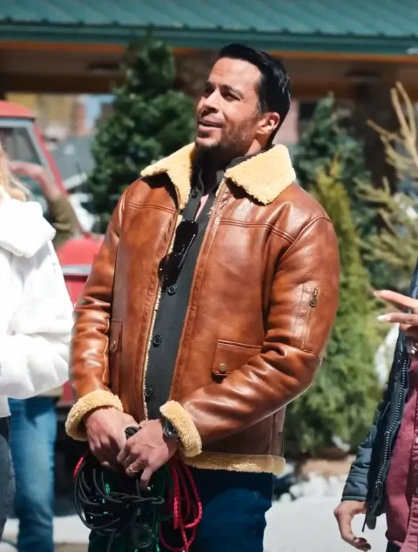 Man in brown shearling leather jacket standing outdoors by Christmas trees