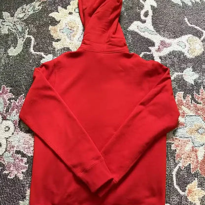 Red hooded sweatshirt laid flat on patterned carpet