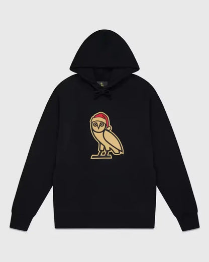 Black OVO Christmas hoodie with gold owl logo wearing a red Santa hat
