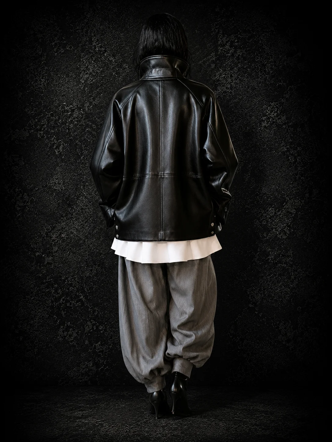Back view of an oversized black leather coat with funnel neck and relaxed silhouette